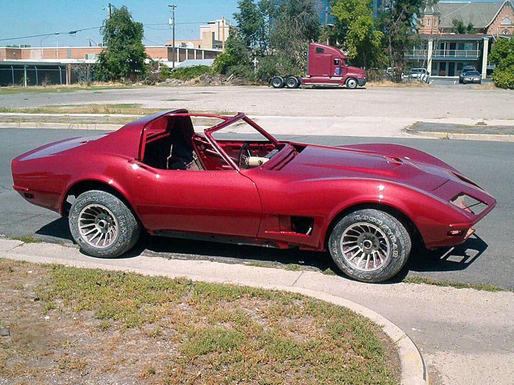 fully painted glossy red classic Corvette convertible outside, looking restored.