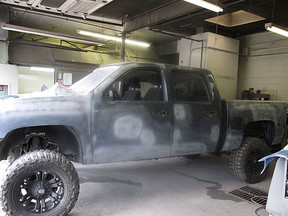 Gray pickup truck in a shop, prepped for painting with a dull, sanded surface