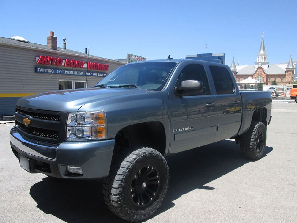 Newly painted dark gray pickup truck, shining brightly outside the auto body shop.