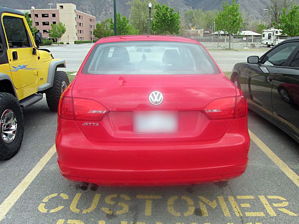 Same red Volkswagen Jetta after rear bumper repair, parked outside.