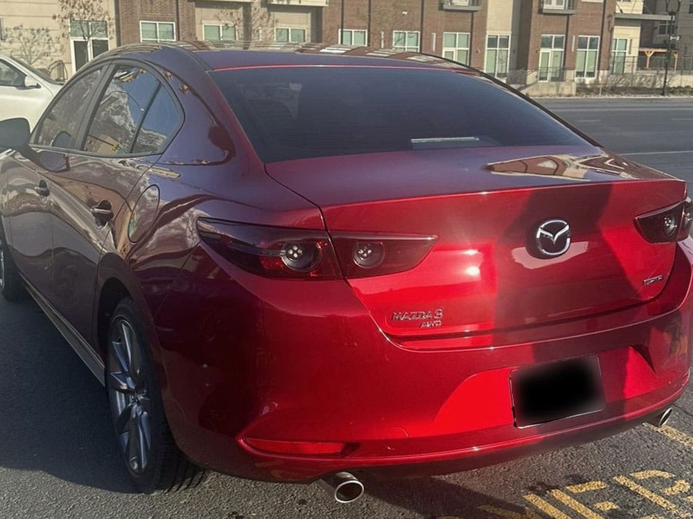 Image of a pristine red Mazda 3 sedan after rear repair, shining in sunlight.