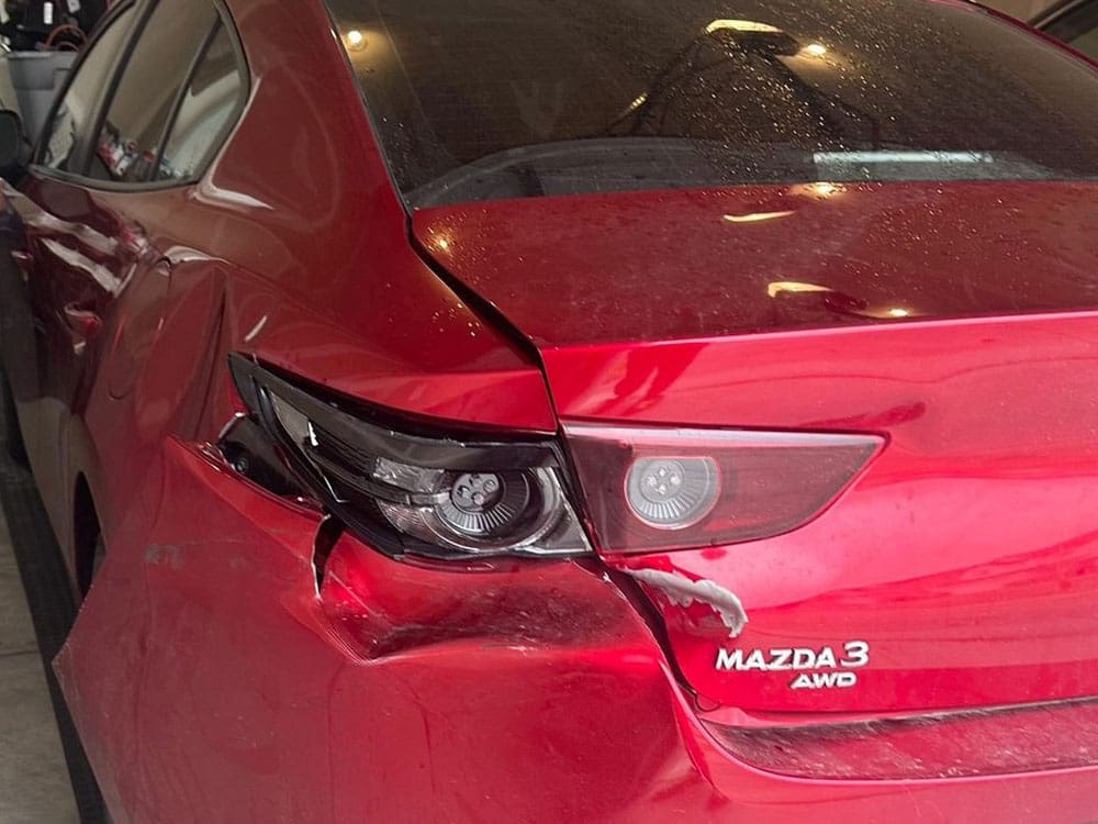 Image of a red Mazda 3 sedan with significant rear collision damage to bumper and taillight.