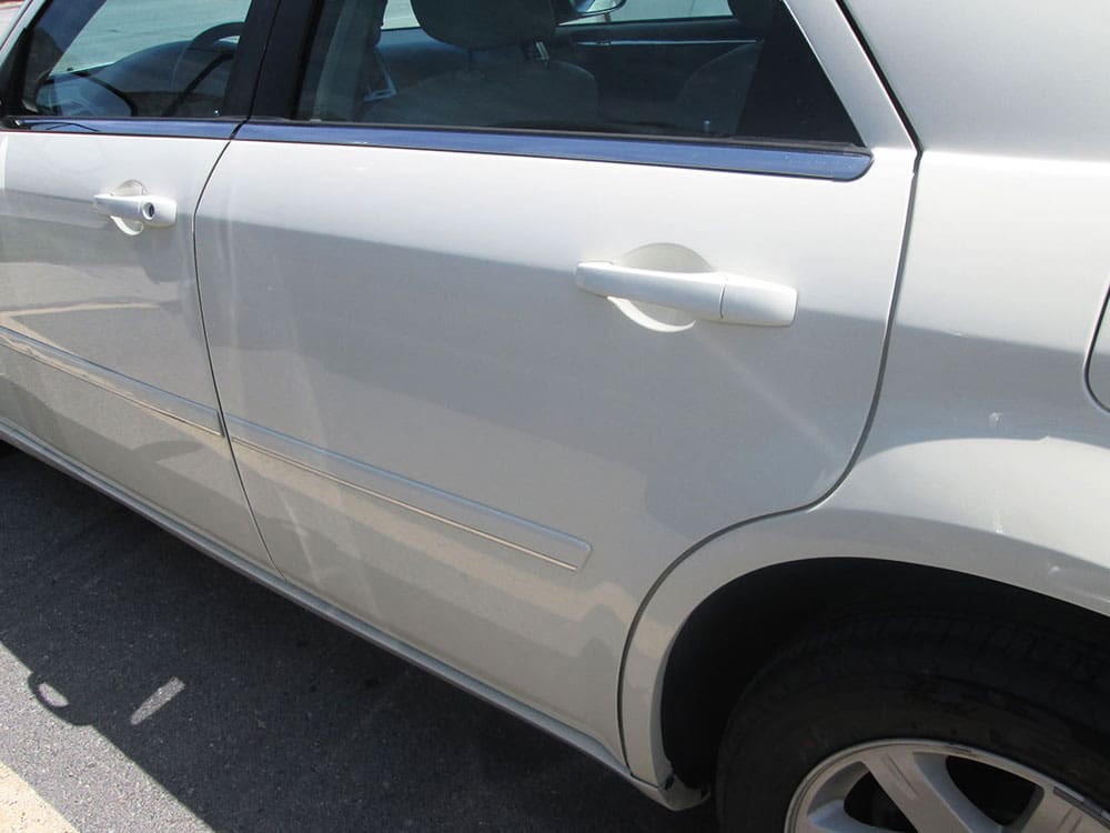 The same white car after dent and body repair, side view